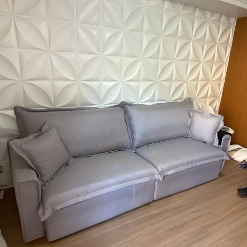 Sofá Cama Ágata em linho cinza claro, fechado, encostado numa parede de painel 3D branco