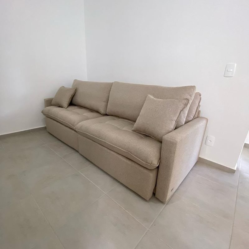 Sofá Cama Manchester em linho bege, com o capitonê do assento à vista, numa sala de piso claro